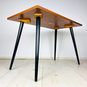Peut inclure: Une table de style moderne du milieu du si&egrave;cle avec un plateau en bois et des pieds noirs. La table a un design simple et est parfaite pour un petit espace.