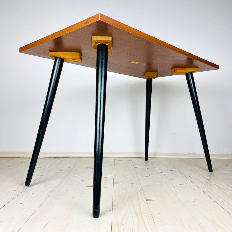 Peut inclure: Une table de style moderne du milieu du si&egrave;cle avec un plateau en bois et des pieds noirs. La table a un design simple et est parfaite pour un petit espace.