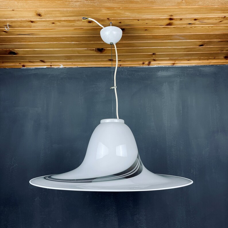 May include: A white pendant light with a black and white striped glass shade. The shade is shaped like a wide, shallow bowl.