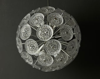 Puede incluir: Una lámpara de araña de plata y cristal con forma esférica y múltiples paneles de vidrio circulares. La lámpara de araña tiene un diseño moderno y es perfecta para un hogar contemporáneo.