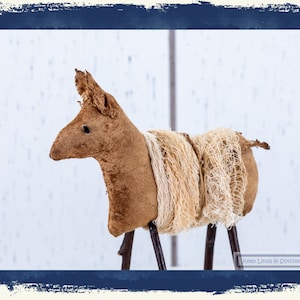 May include: A handcrafted brown fabric donkey figurine with a textured mane and tail, standing on twig legs. The donkey has a rustic, homespun aesthetic, perfect for farmhouse decor. The donkey is approximately 8 inches tall.