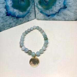 May include: A light blue gemstone bracelet with a gold charm that says "Homes".