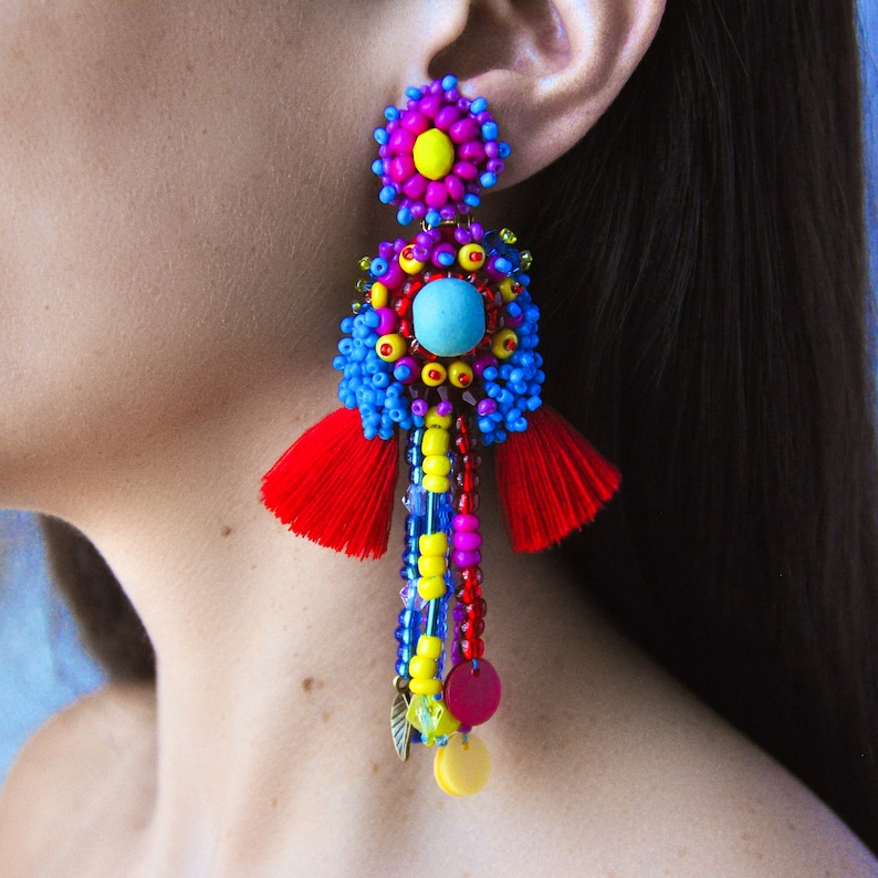 May include: Colorful beaded earrings with a turquoise stone, red tassels, and yellow, blue, pink, and red beads.