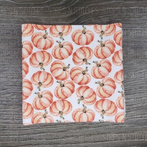 May include: White fabric with a repeating pattern of orange watercolor pumpkins.
