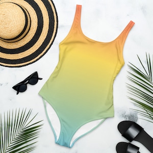 May include: A one-piece swimsuit with a gradient design, transitioning from orange to yellow to green to blue. The swimsuit has a scoop neck and thin straps.