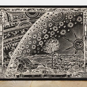 Puede incluir: Impresión enmarcada en blanco y negro con una detallada ilustración celestial. La obra de arte representa estrellas, el sol, la luna, nubes y un árbol, con una figura en primer plano. La impresión tiene un borde decorativo.