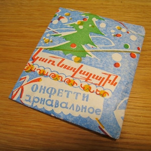 May include: A blue and white paper packet of confetti with a green Christmas tree design and the text "Confetti Carnival" in red and yellow letters.