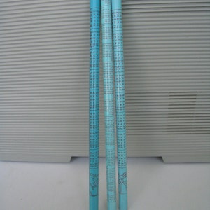 Può includere: Tre bastoncini di legno blu con segni e numeri neri. I bastoncini sono lunghi circa 30 cm e hanno un'estremità arrotondata. I bastoncini sono usati per contare e misurare.