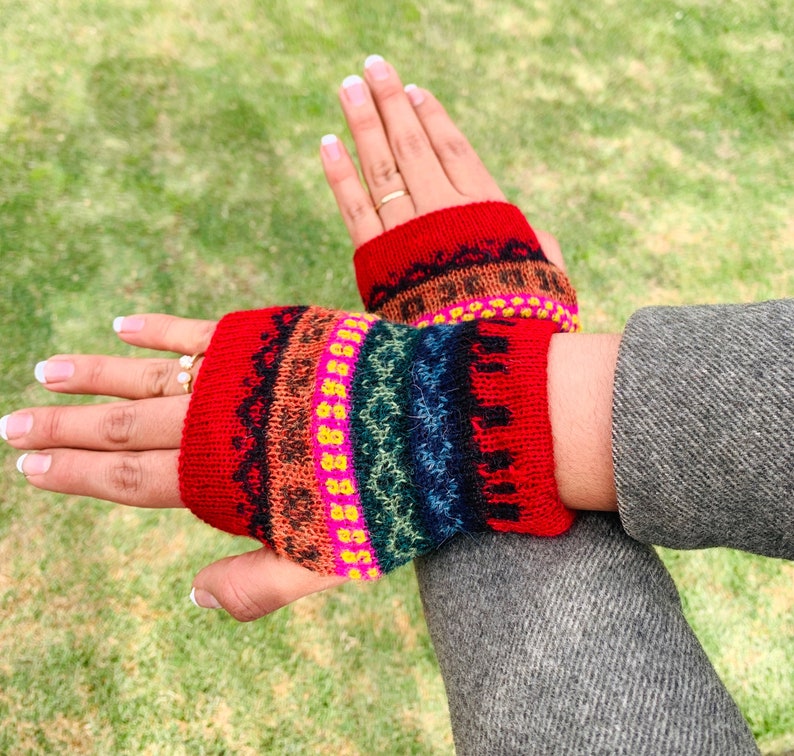 May include: A pair of red knit fingerless gloves with a colorful geometric pattern. The gloves are made of a soft, warm material and are perfect for keeping your hands warm in the winter.