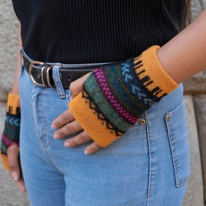 May include: A pair of knitted fingerless gloves with a colorful geometric pattern. The gloves are mustard yellow with blue, green, pink, and black accents.
