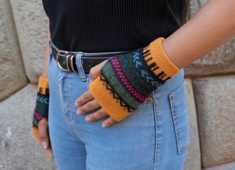 May include: A pair of knitted fingerless gloves with a colorful geometric pattern. The gloves are mustard yellow with blue, green, pink, and black accents.