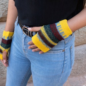 May include: A pair of yellow fingerless gloves with a colorful geometric pattern. The gloves are made of knitted wool and have a warm, cozy feel.