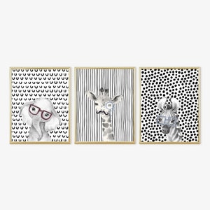 May include: Three framed prints featuring black and white illustrations of an elephant, giraffe, and zebra wearing glasses. Each print has a different black and white patterned background.