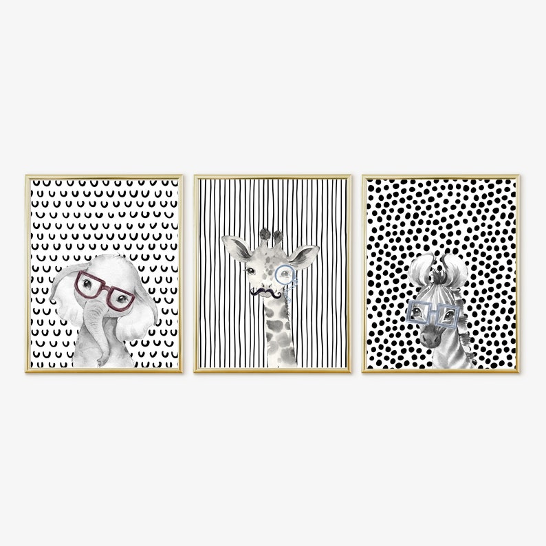 May include: Three framed prints featuring black and white illustrations of an elephant, giraffe, and zebra wearing glasses. Each print has a different black and white patterned background.