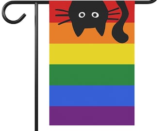 May include: A rainbow pride flag with a black silhouette of a cat looking over the top. The flag is attached to a black metal garden flag stand.
