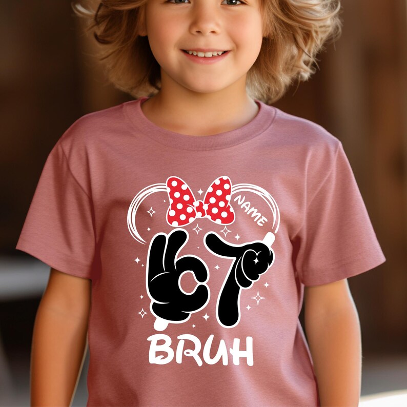 Puede incluir: Una camiseta malva con un dise&ntilde;o tem&aacute;tico de Minnie Mouse para un ni&ntilde;o de 6 a&ntilde;os. El dise&ntilde;o incluye un lazo de lunares rojos y blancos, manos de dibujos animados negras que forman el n&uacute;mero 67 y la palabra "BRUH" en blanco. Hay espacio para un nombre.