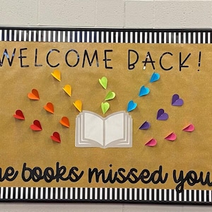 May include: A bulletin board with the words "WELCOME BACK!" and "the books missed you" in black lettering. A paper book is surrounded by colorful paper hearts in a rainbow pattern. The board has a black and white striped border.