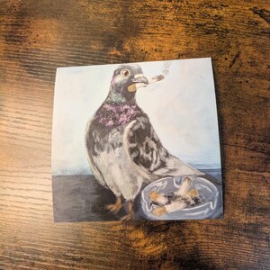 May include: A square print featuring a pigeon with a lit cigarette in its beak, and an ashtray with cigarette butts. The pigeon has purple and gray feathers. The background is a light blue.
