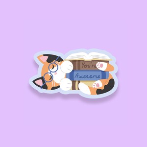 May include: A calico cat wearing glasses sleeps on top of a stack of books. The top book has the text "You're Awesome" on the cover.