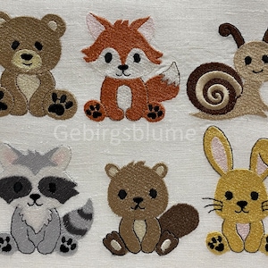 Puede incluir: Seis aplicaciones de animales de fieltro bordadas en varios colores, incluyendo un oso marrón, un zorro naranja, un caracol marrón, un mapache gris, una ardilla marrón y un conejito amarillo.