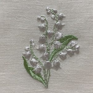 May include: Embroidered lily of the valley flowers in silver thread on a white linen fabric.