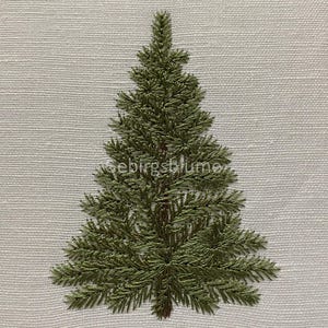 Puede incluir: Diseño bordado de árbol de Navidad en tonos verdes y marrones sobre tela gris claro. El árbol está centrado y detallado, con costuras visibles. El texto "seebirgsblume" es visible en la parte inferior derecha de la imagen.