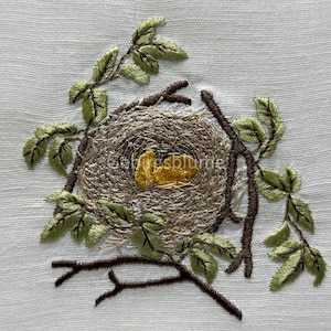 May include: Embroidered design of a bird's nest with two yellow eggs inside, surrounded by green leaves and brown branches.
