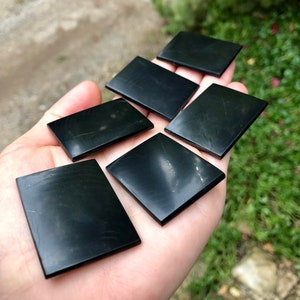 May include: Six black polished stone rectangular shapes, likely for use in a craft project or as decorative elements.