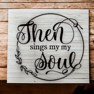 May include: A white wooden sign with a black circle and the text "Then sings my soul" in a decorative font.