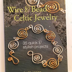 May include: A softcover book titled Wire & Bead Celtic Jewelry by Linda Jones. The cover features a dark gray textured background with a photograph of a bracelet made from interconnected gold and silver wire spirals. Text reads 35 quick & stylish projects.