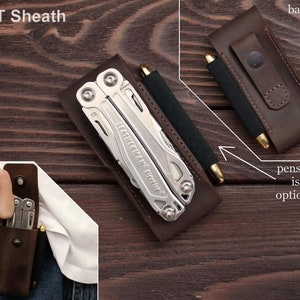 Pu&ograve; includere: Un fodero in pelle marrone per un multi-utensile con il testo "MT Sheath" in alto. Il fodero ha una fessura per una penna o una matita sul retro. Il testo "penslip is optional" &egrave; sotto la fessura.