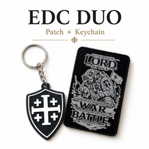Op de afbeelding: Een zwarte rechthoekige patch en een schildvormige sleutelhanger. De patch toont een illustratie van een soldaat met de tekst BLESSED BE THE LORD MY ROCK WHO TRAINS MY HANDS FOR WAR AND MY FINGERS FOR BATTLE PSALM 144:1. De sleutelhanger toont een wit kruis.