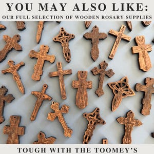 May include: A collection of intricately carved wooden crosses in various designs. The crosses are brown and feature detailed religious imagery. The image includes the text "YOU MAY ALSO LIKE: OUR FULL SELECTION OF WOODEN ROSARY SUPPLIES" and "TOUGH WITH THE TOOMEY'S".