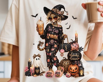 May include: A cream-colored t-shirt featuring a graphic of a leopard-print witch wearing sunglasses and a hat, holding a coffee cup. The text reads Too Cute to SPOOK and SPOOKY SEASON. The design includes pumpkins, a ghost, and candles.