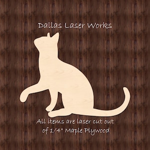May include: Laser cut wooden silhouette of a cat sitting with its tail curled around its legs. The cat is made of 1/4 inch maple plywood. "Dallas Laser Works" and "All items are laser cut out of 1/4" Maple Plywood" are written below the cat.