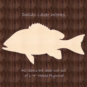 May include: A laser-cut wooden cutout of a fish, made from 1/4 inch maple plywood. The fish is a light brown color and has a detailed outline. The text "Dallas Laser Works" is at the top of the image, and the text "All items are laser cut out of 1/4" Maple Plywood" is at the bottom.