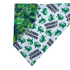 May include: A white bandana with a green and black tropical leaf pattern on one side and a white side with green lizards and the text "Lizard Chaser" repeated.