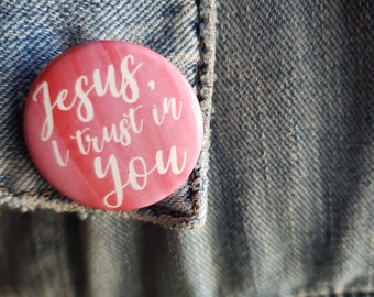 May include: Pink button with the text "Jesus, I trust in you" in white cursive lettering.