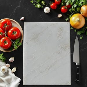 May include: A white marble cutting board with a stainless steel knife, surrounded by fresh ingredients like tomatoes, onions, garlic, and herbs. The ingredients are arranged on a dark surface, creating a visually appealing composition for culinary use.