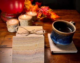 May include: Set of four sandstone coasters with a rustic, natural look. The coasters are tied together with twine and are perfect for protecting surfaces from heat and spills.
