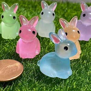 May include: Six pastel colored resin bunny figurines. The bunnies are in various poses and are made of a translucent material. The colors are light green, pink, white, light blue, and light purple.