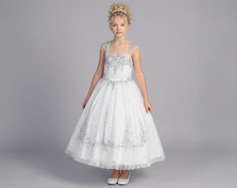 May include: A white floor-length dress featuring silver embroidery on the bodice and skirt, cap sleeves with fringe detailing, a sweetheart neckline, and a full tulle skirt. The dress is paired with a silver tiara worn on the head.