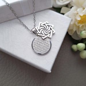 May include: A silver necklace with a pendant featuring a stylized eight-pointed star and a round charm with an inscription in Armenian. The inscription reads: "Հայր մե որ յերկինս ւրբ եղիցի անու Եկեսցէ արքայութիւն Քո։ Եղիցին կամք Քո որ պէս յերկինս և յերկրի։ Զհաց մեր հանապազո րդ տուր մեզ այսօր: և թող մեզ զպա ոտիս մեր, "