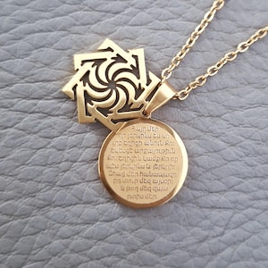 May include: Gold necklace with a pendant featuring a stylized eight-pointed star and a round charm with Armenian text. The text reads: "Հայր մեր որ յերկինս ես un ւրբ եղիցի անուն Քո։ Եկեսցէ արքայութիւն Քո։ Եղիցին կամք Քո որ պէս յերկինս և յերկրի: Զհաց մեր հանապազո րդ տուր մեզ այսօր: և թող մեզ զպ արտիս մեր"