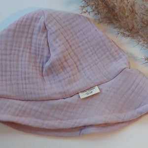 May include: A pale pink, soft cotton bucket hat with a small label that reads "The Little Wren" on the side.