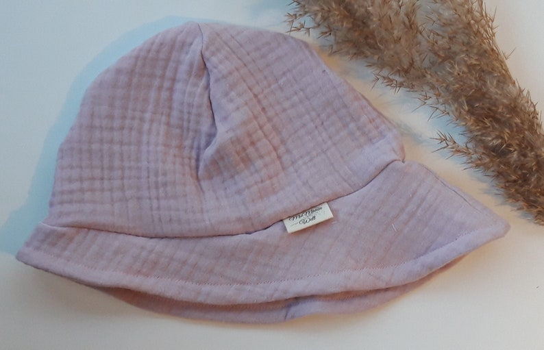 May include: A pale pink, soft cotton bucket hat with a small label that reads "The Little Wren" on the side.