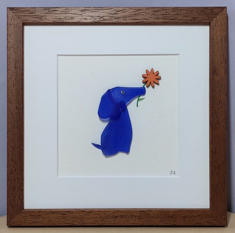 May include: A framed artwork featuring a blue glass dog sniffing an orange flower. The artwork is signed "M.R."