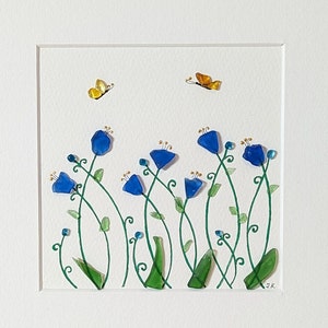 May include: A blue and green glass art piece depicting a field of blue flowers with green stems and leaves. Two yellow butterflies are flying above the flowers.