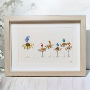 May include: Framed artwork featuring a pebble art design of colourful birds perched on yellow flowers. The birds are made of painted stones and the flowers are made of pebbles. The artwork is signed "JC".