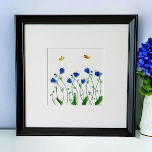 May include: Framed artwork featuring a watercolor painting of blue flowers with green stems and yellow butterflies on a white background.